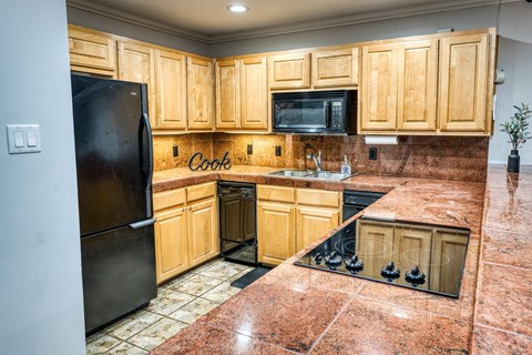 a kitchen with wooden cabinets and a black refrigerator